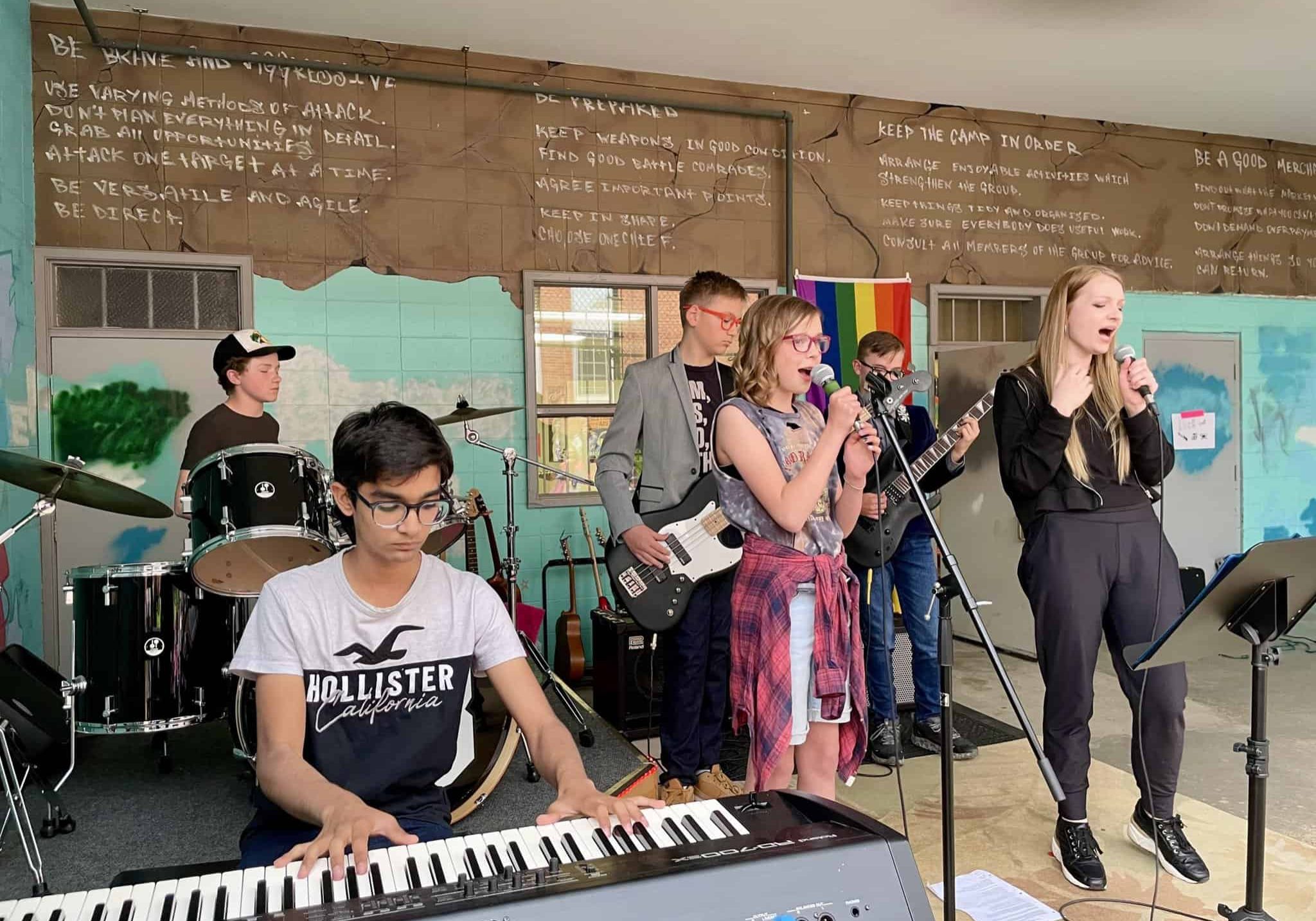 Brokend Glasses, Youth Rock Band at Backbeat Five teenagers plus their teacher are performing at an outdoor Rock Show. At the front is Ayush Shmabhavi, who is playing keyboard.